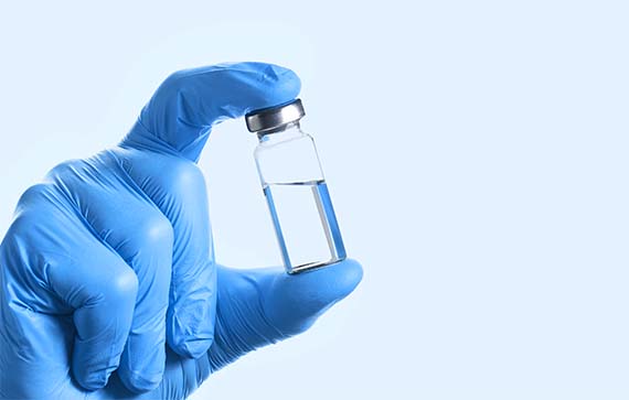 Image Doctor's Hand in blue gloves hold the vial with va