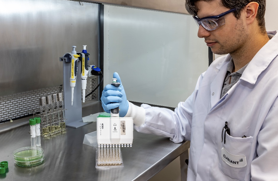 Scientist in a lab coat using a multichannel pipette to transfer liquid samples in a sterile laboratory environment.