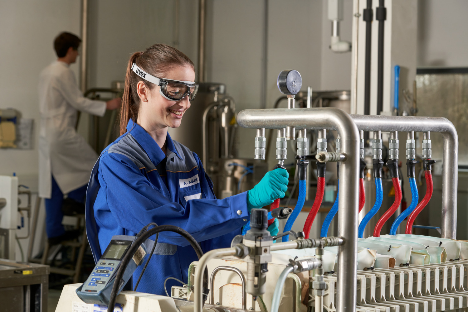 Technician in blue coveralls adjusting filtration equipment in a laboratory
