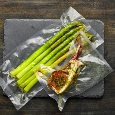 Photo_Lamb rib and vegetables vacuum sealed on wooden table, food packaging