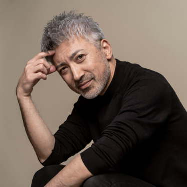 Portrait of a handsome middle-aged man with gray hair and a beard.He is sitting,posing and smiling. (2)